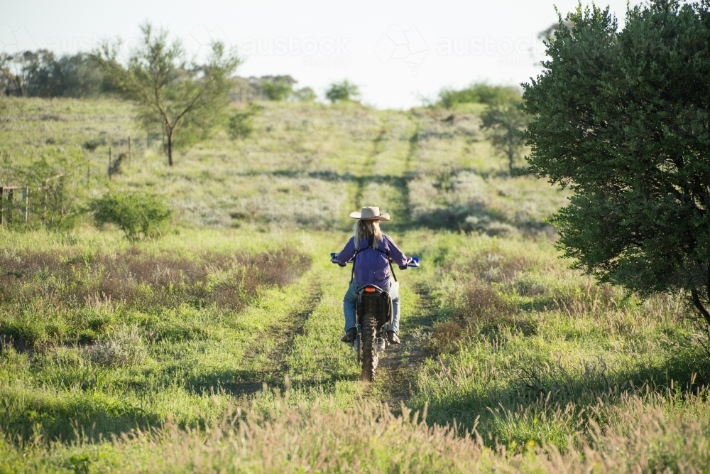 Girl riding motorcycle away from the camera - Australian Stock Image