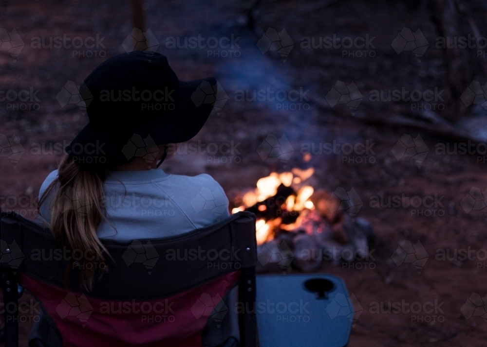 Girl sitting by campfire in the bush - Australian Stock Image