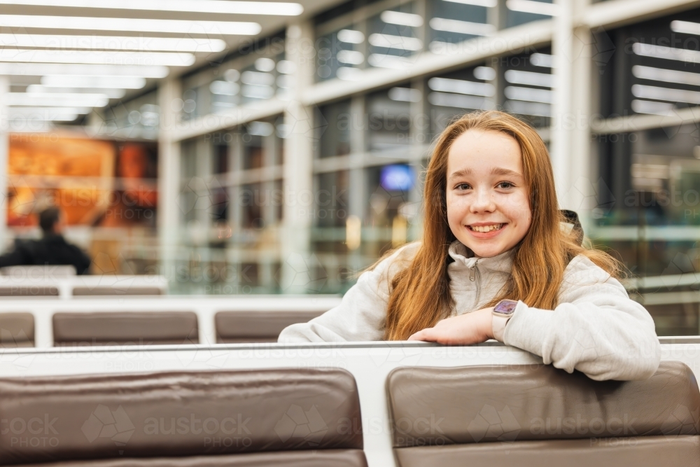 Girl sitting in airport departure lounge waiting for flight - Australian Stock Image