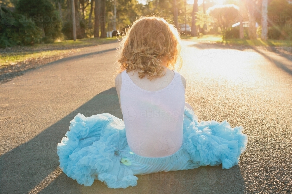 Girl sitting on a road in a blue tutu skirt - Australian Stock Image