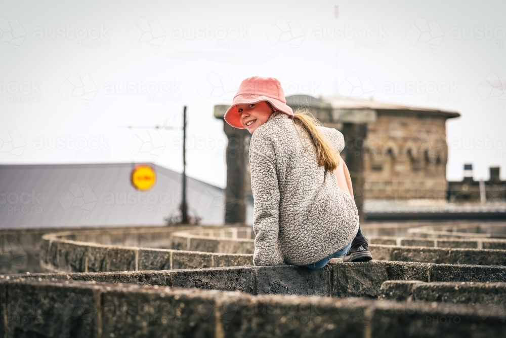 Girl sitting on maze wall at Kryal Castle, Ballarat Victoria Australia - Australian Stock Image