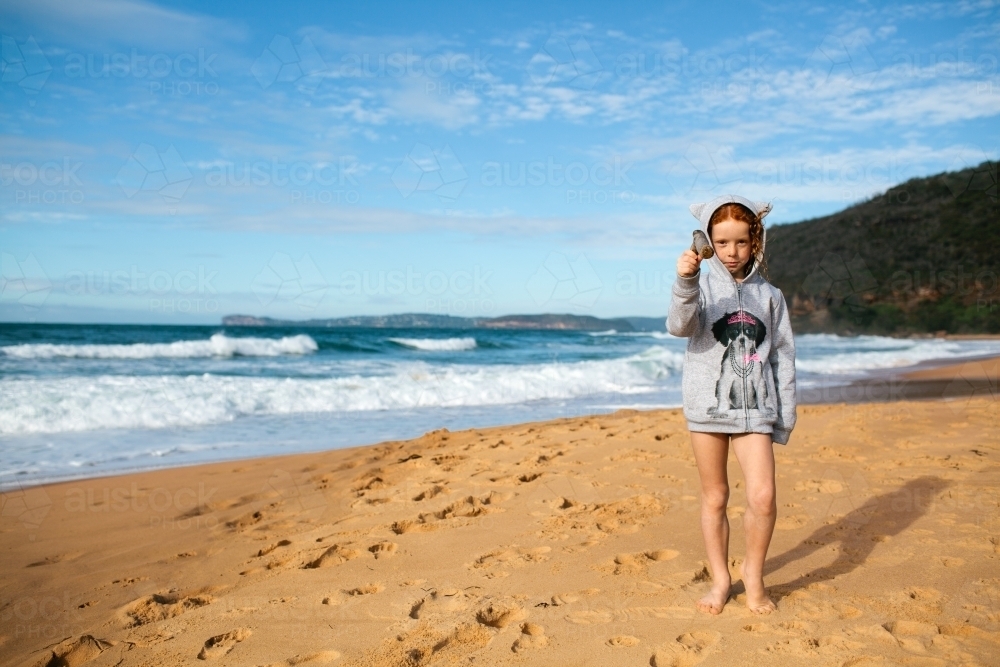 Girl standing on a beach in a grey jumper - Australian Stock Image