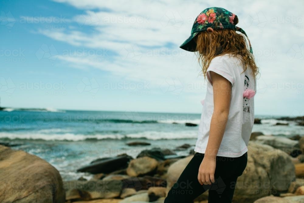 Girl walking on rocks at the beach - Australian Stock Image