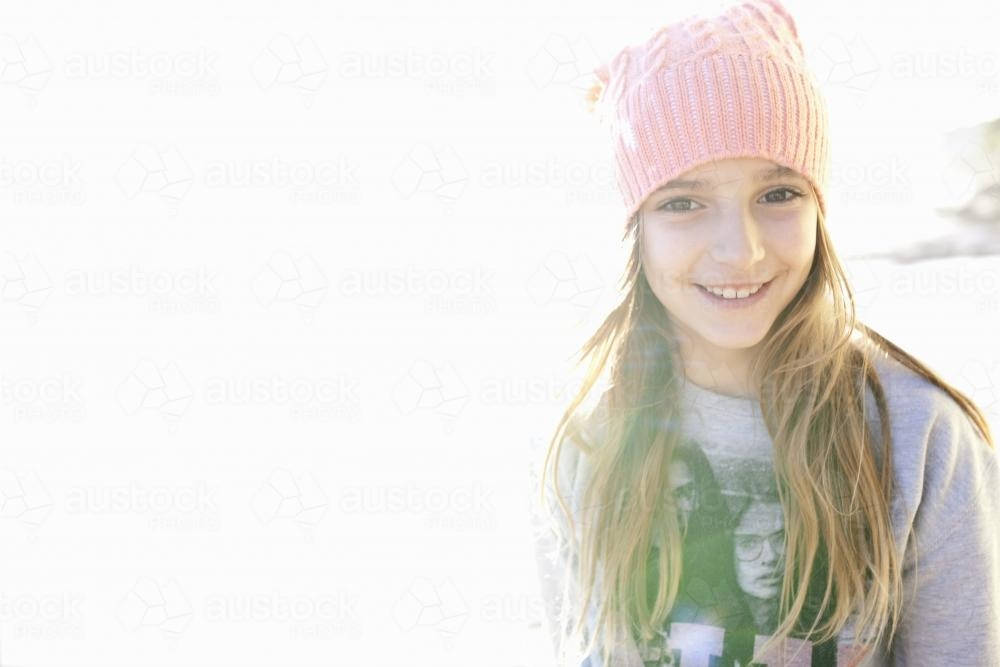 Girl wearing a beanie smiling with sunlight on background - Australian Stock Image