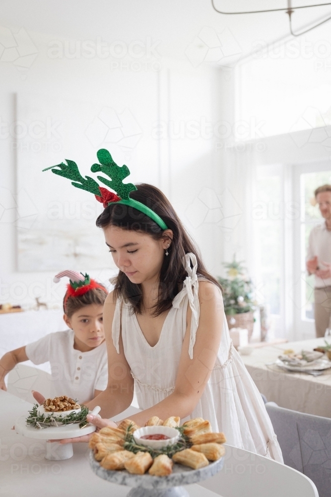Girl wearing antler headband setting up table - Australian Stock Image
