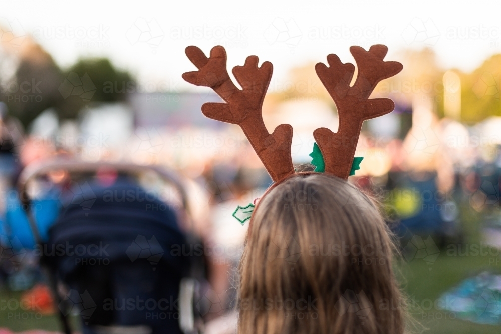 girl wearing antlers watching carols in a crowd - Australian Stock Image