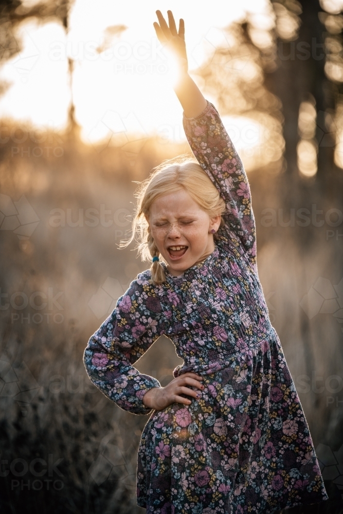 Girl with hand on hip and up in the air dancing in the sunshine - Australian Stock Image