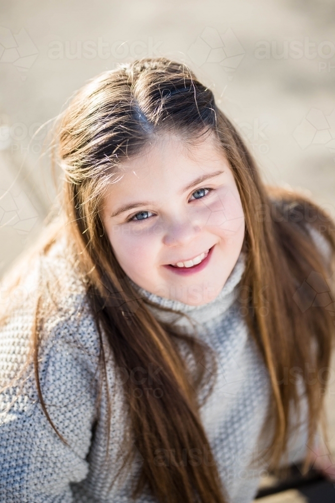 Girl with long hair smiling looking up - Australian Stock Image