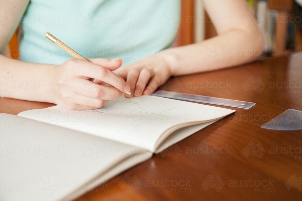 Girl writing in blank graph paper school book - Australian Stock Image