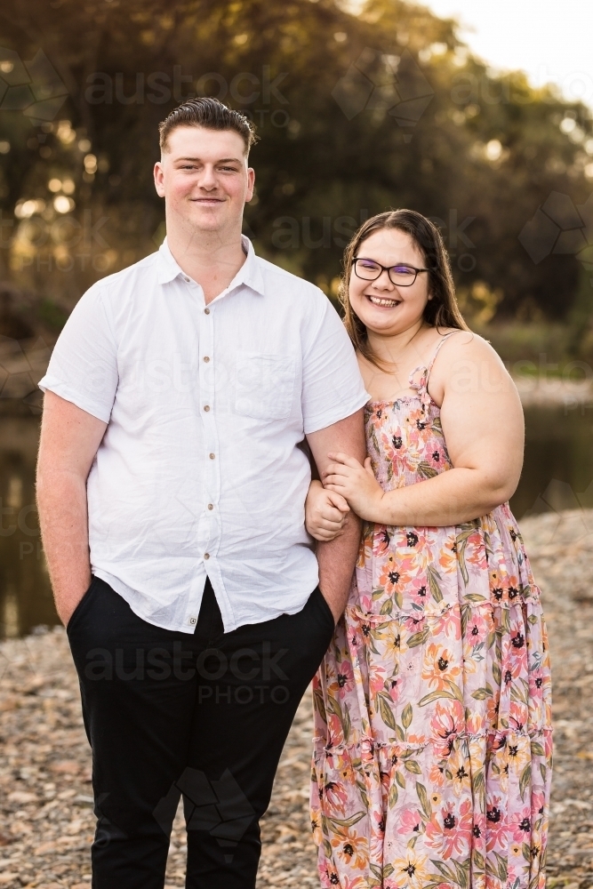 Girlfriend holding onto boyfriends arm smiling - Australian Stock Image