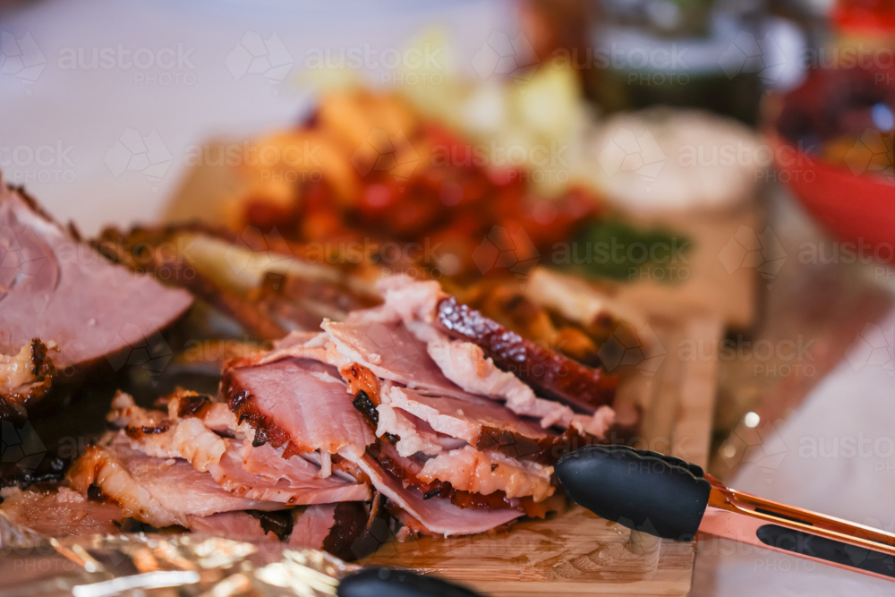 Glazed ham sliced on table with spread for Christmas lunch - Australian Stock Image