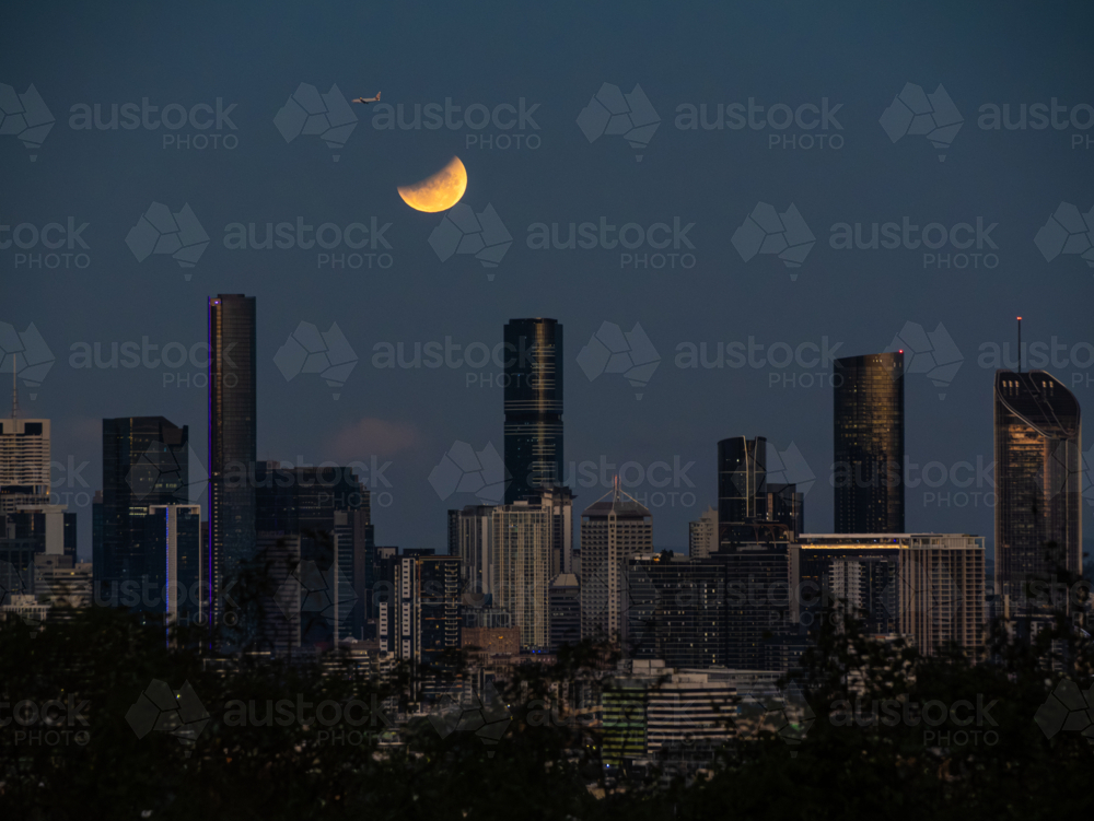 Glowing eclipse of the full moon shining over city skyline - Australian Stock Image