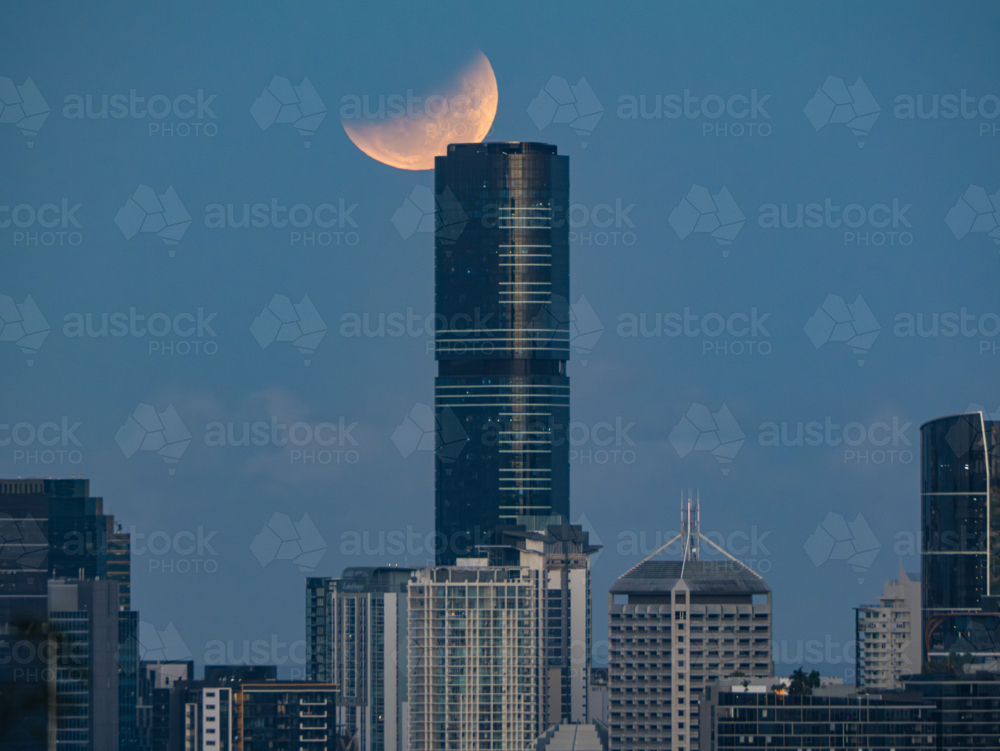 Glowing eclipse of the full moon shining over city skyline - Australian Stock Image