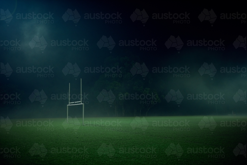 Goal posts on empty sports oval in the fog at night - Australian Stock Image