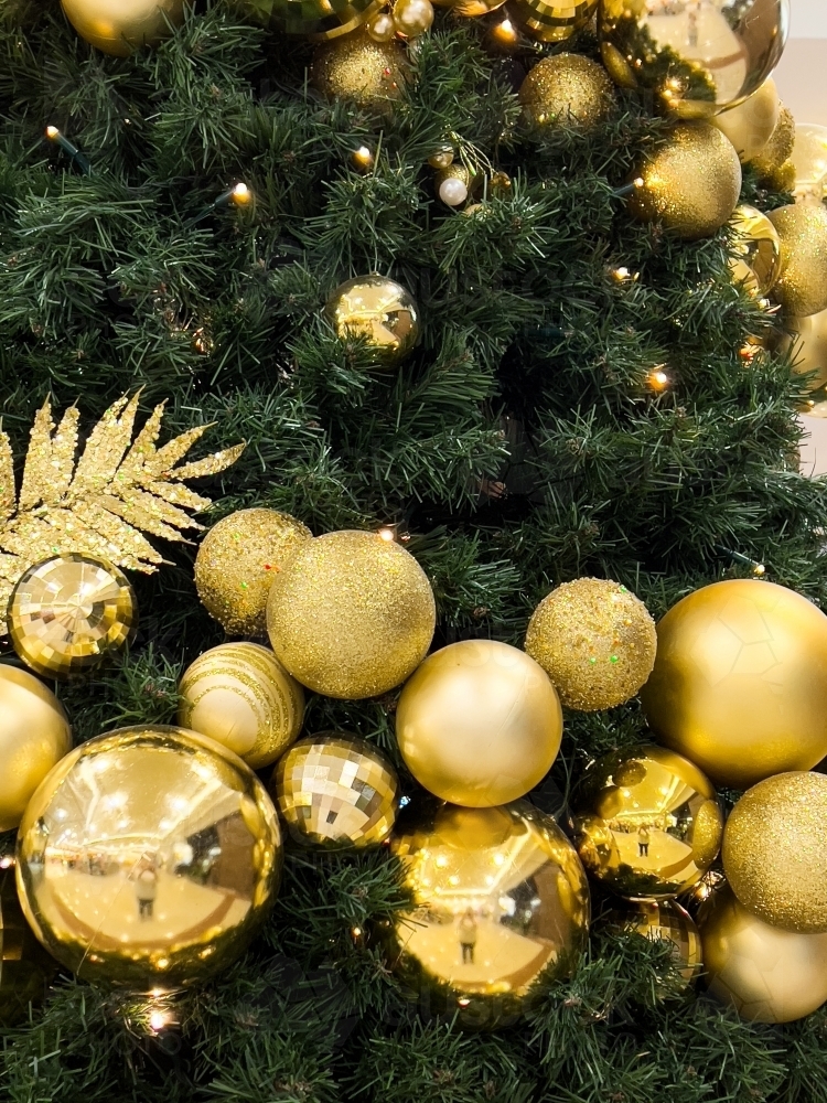 Golden metallic balls decorating a christmas tree with reflections - Australian Stock Image