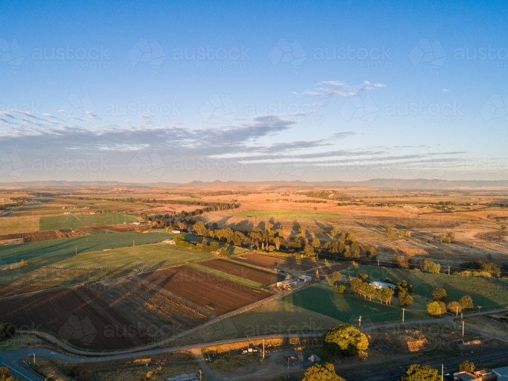 Golden sunrise over farmland with trees leaving long shadows - Australian Stock Image