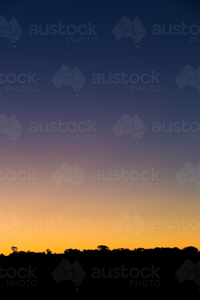 Graduated colour on twilight night sky, with silhouette skyline - Australian Stock Image