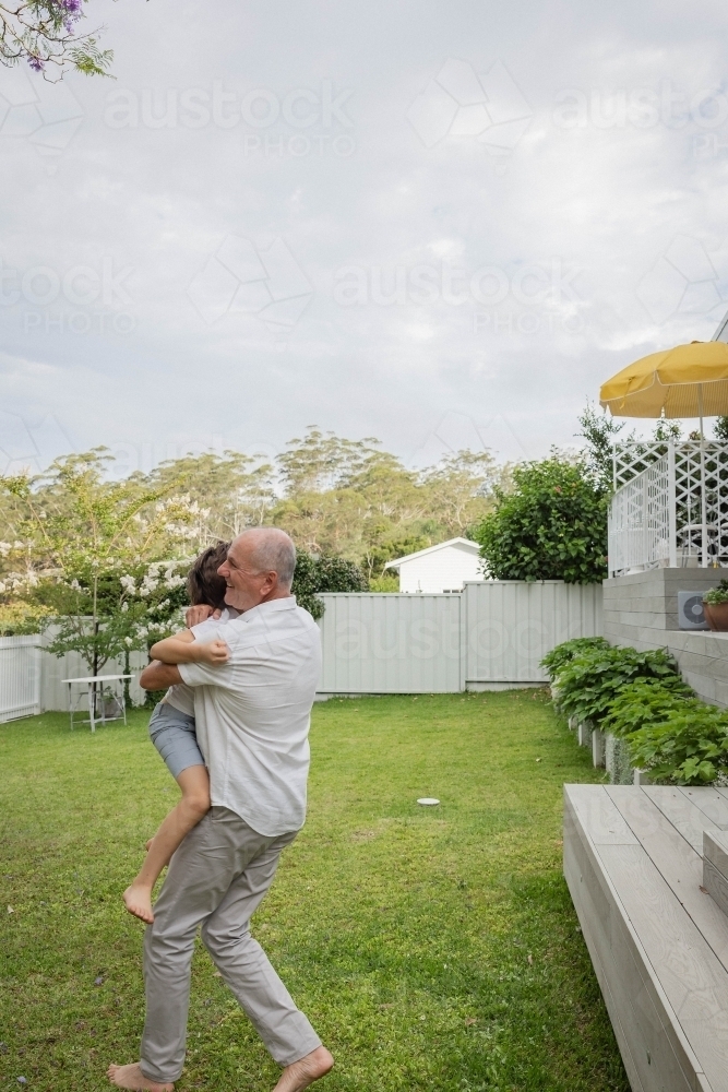 Image of Grandad and grandson hugging in backyard - Austockphoto