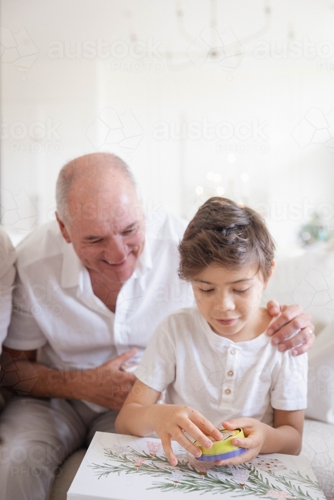 Grandad with grandson opening Christmas present - Australian Stock Image