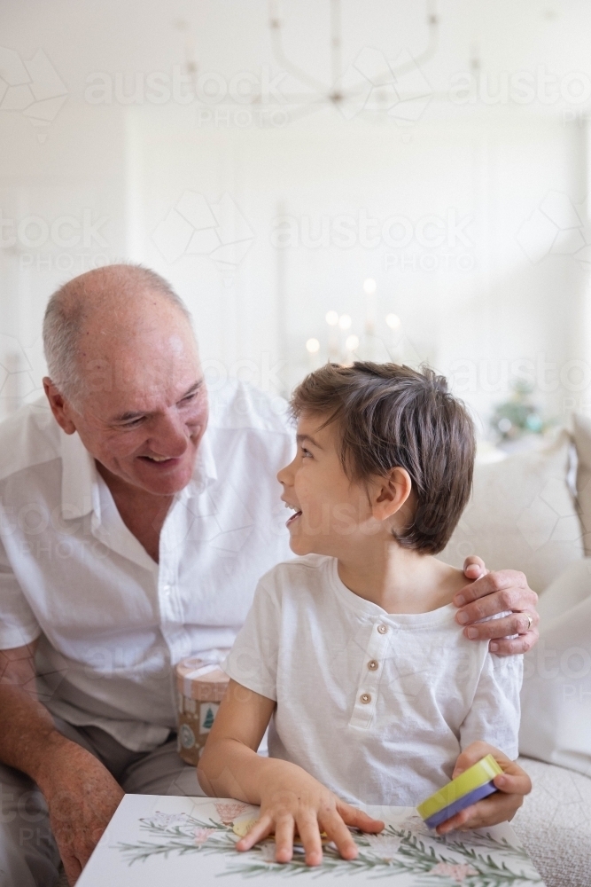 Image of Grandad with grandson opening Christmas present - Austockphoto