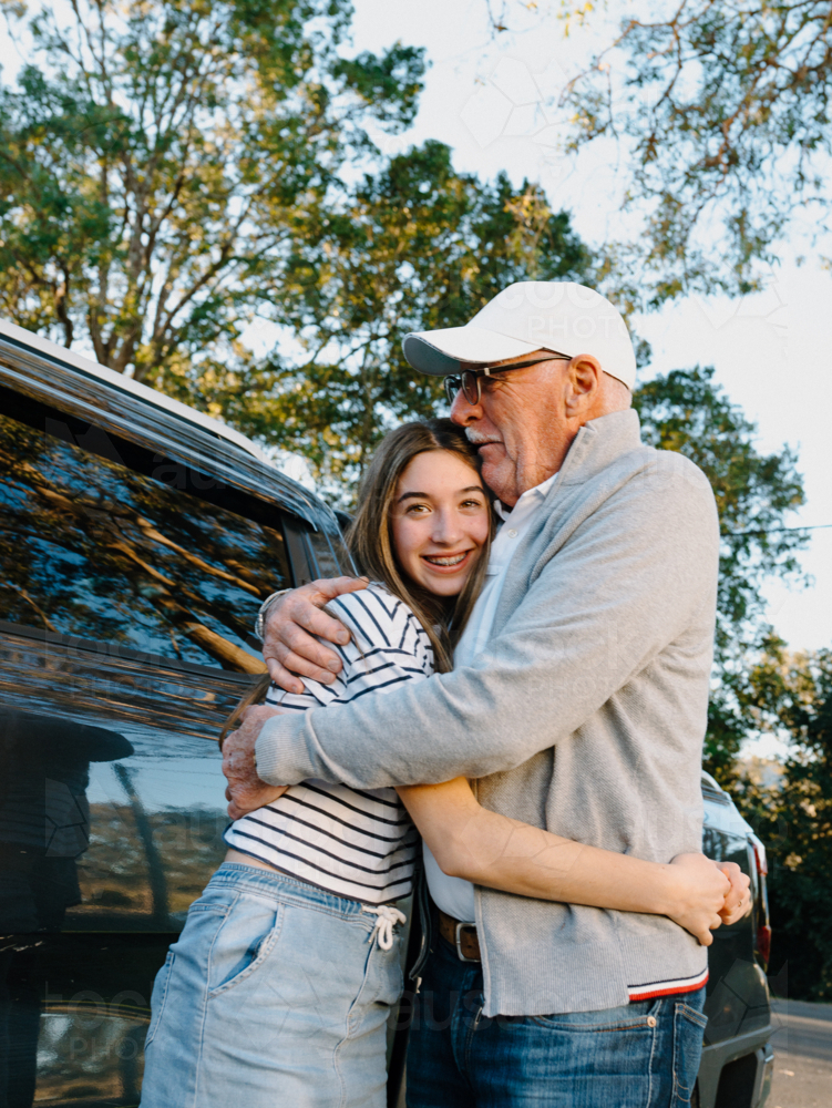 Grandfather embracing granddaughter outside the house. - Australian Stock Image