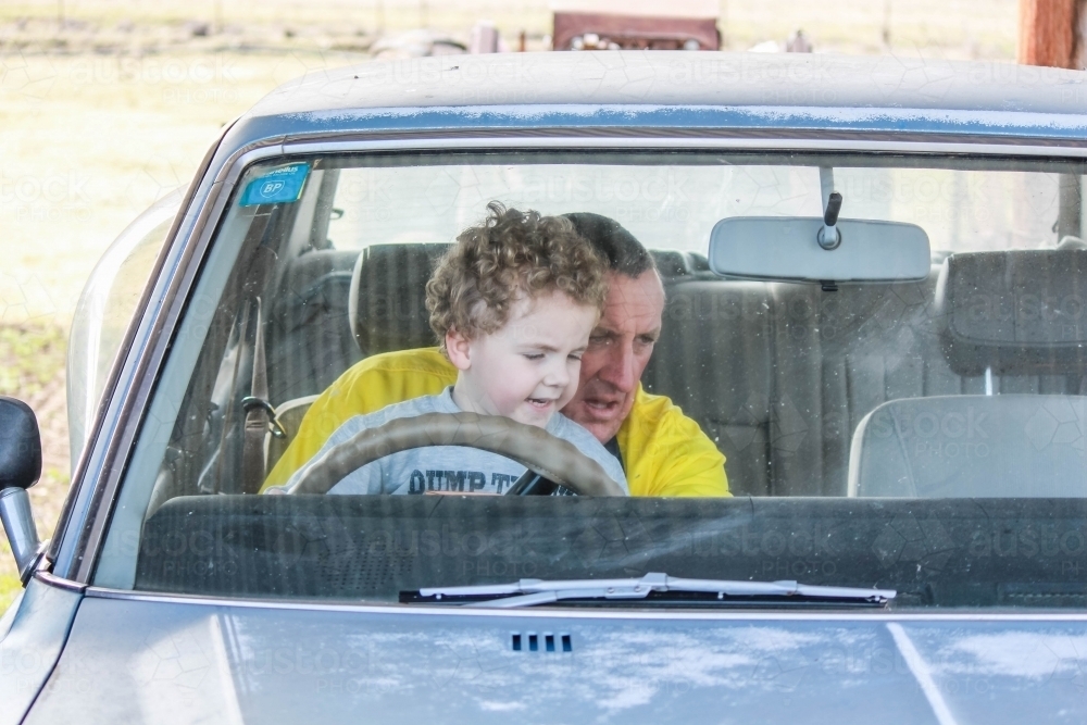 Grandfather sitting with grandson in old car - Australian Stock Image