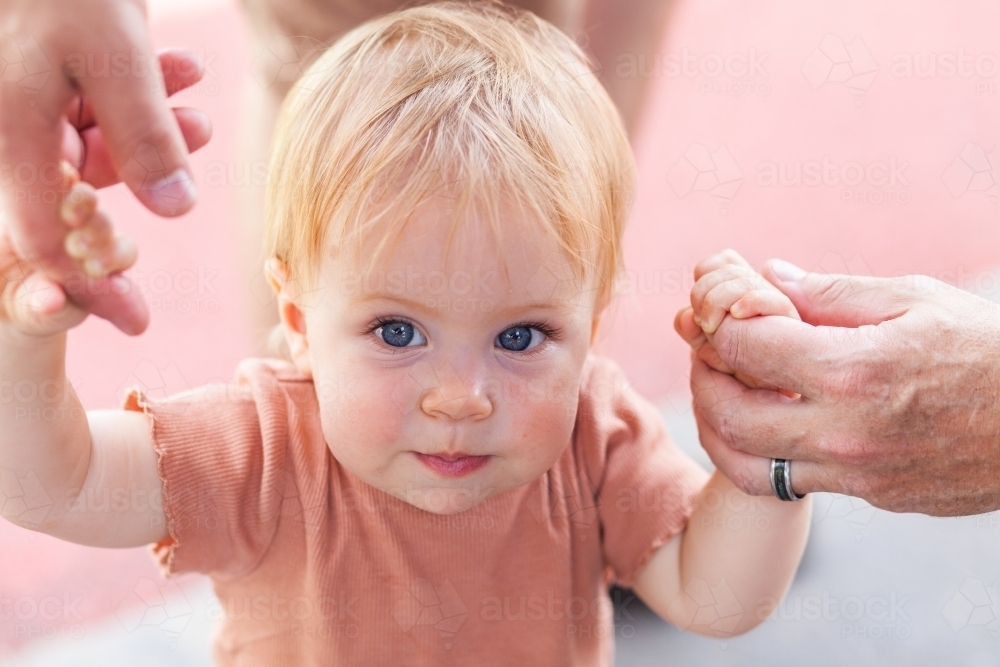 Grandfathers hand holding baby's hand helping baby to walk - Australian Stock Image