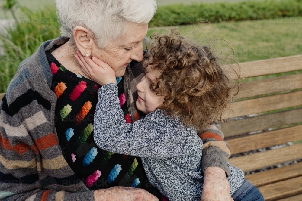 Grandmother and grandson hugging on a park bench - Australian Stock Image