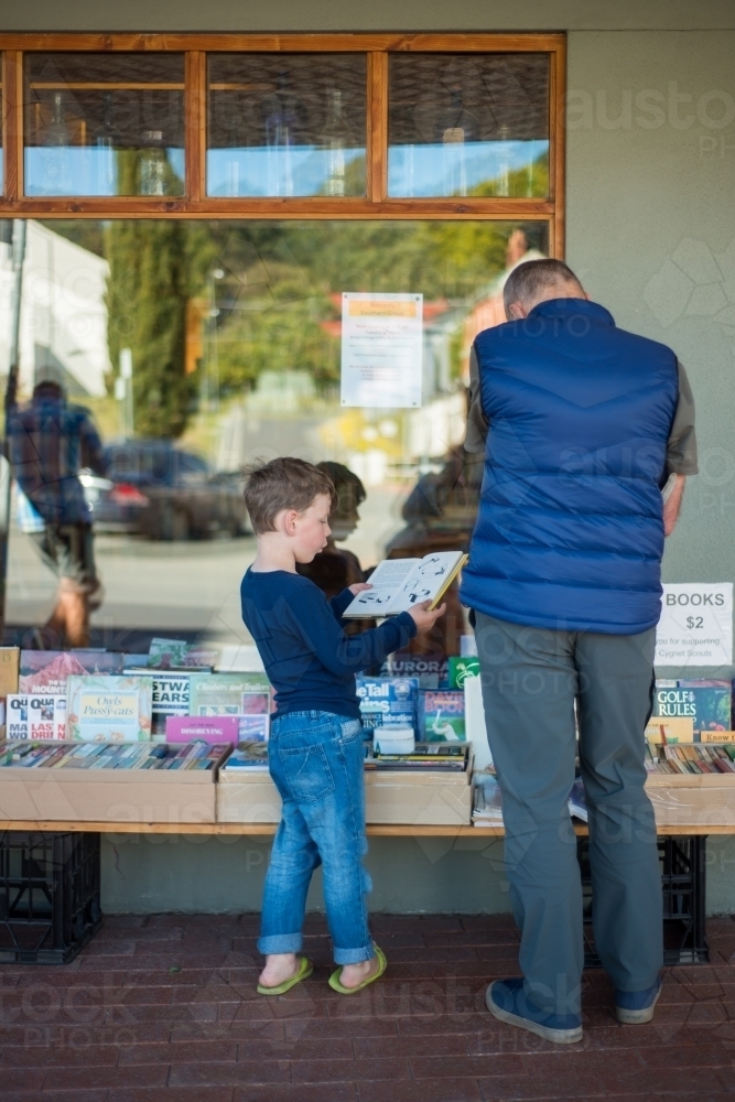 Grandpa and boy reading books at a shop - Australian Stock Image