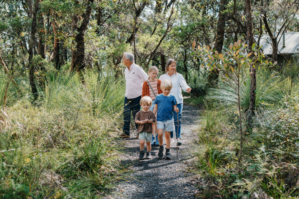 Grandparents enjoying Australian Bushland with their Grandchildren walking down trail - Australian Stock Image