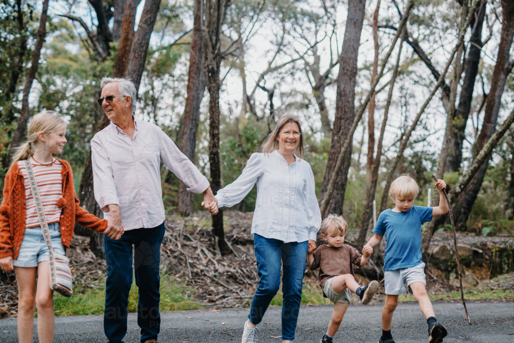 Grandparents enjoying Australian Bushland with their Grandchildren walking while holding hands - Australian Stock Image