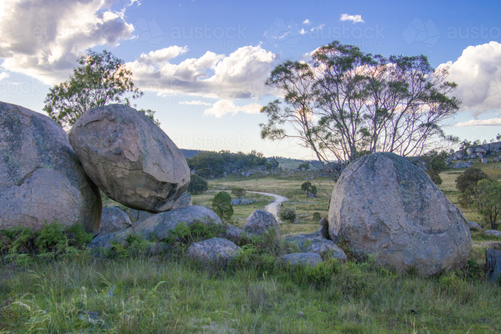 Granite rocks, a winding country road and a cloudy sky - Australian Stock Image