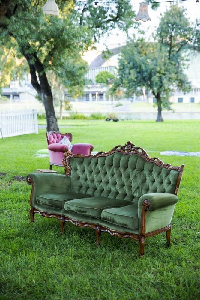 Green velvet couch in garden setting - Australian Stock Image