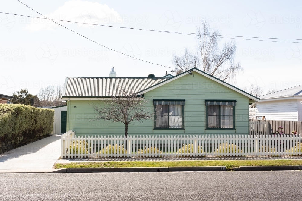 Green weatherboard house with white picket fence - Australian Stock Image