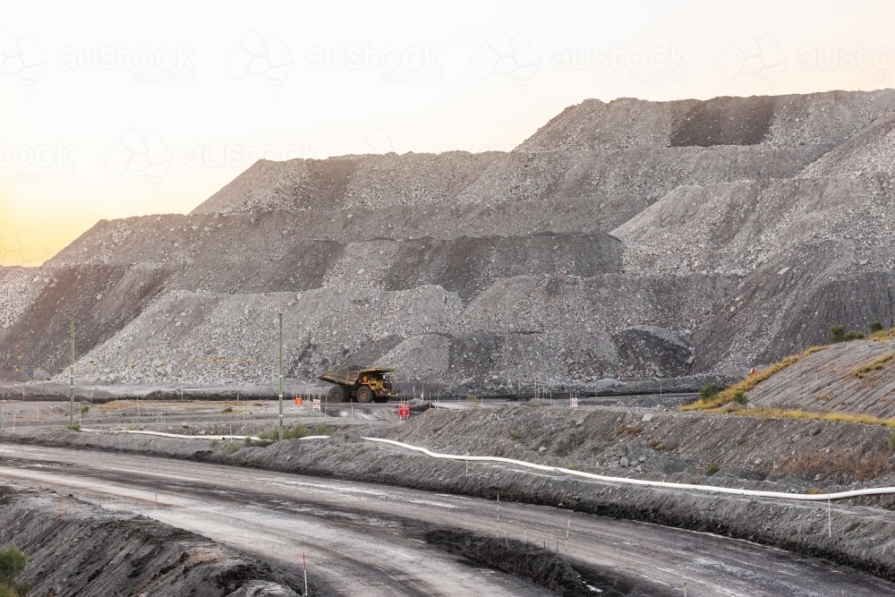 Grey open cut mine hills with dump truck machinery working at earthmoving job - Australian Stock Image