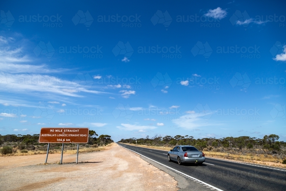 Grey sedan car driving along the 90 Mile Straight on the Eyre Highway on the Nullarbor - Australian Stock Image