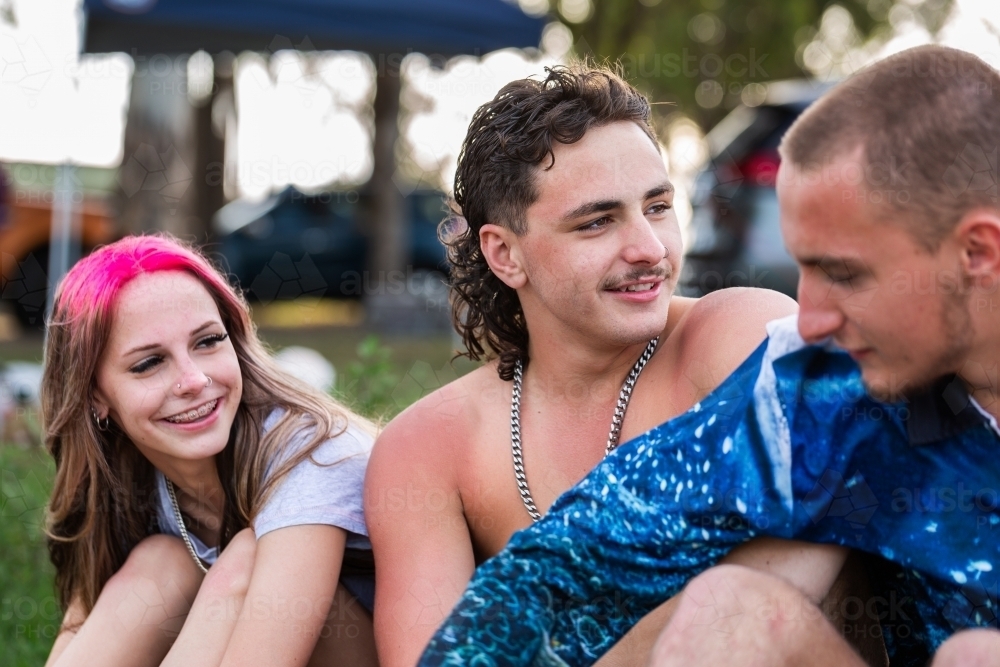 Group of Aussie teens sitting together together on a summer afternoon by a lake - Australian Stock Image