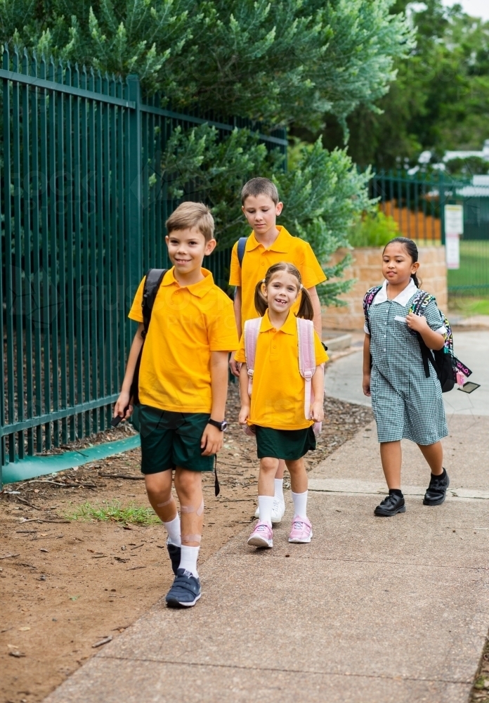 Group of happy kids walking to school together - Australian Stock Image