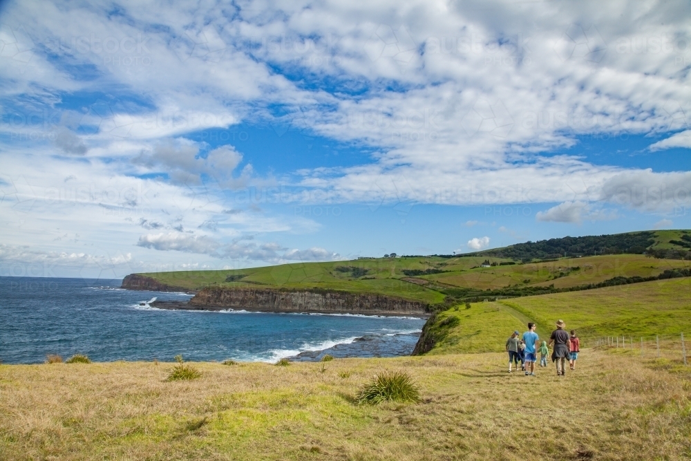 Group of people walking along Kiama Coastal Walk beside the ocean - Australian Stock Image