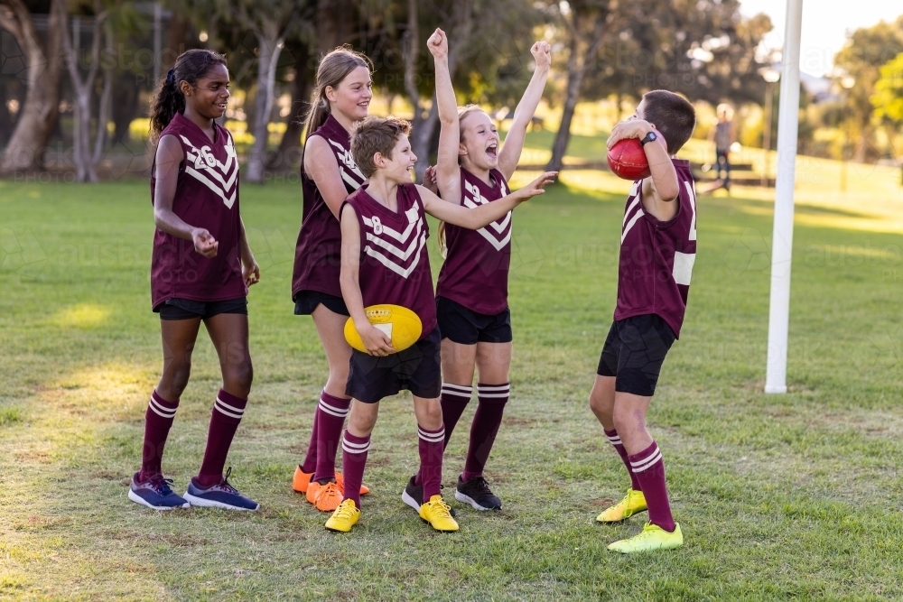 group of school kids in football team cheering each other - Australian Stock Image