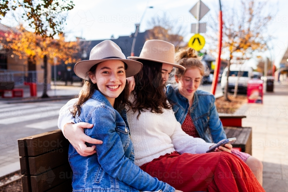 Group of three teenaged friends sitting together in urban area of town - Australian Stock Image