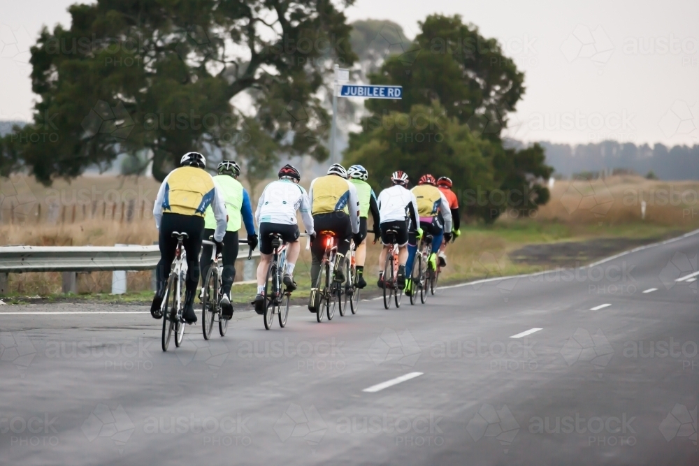 Groups of cyclists riding in single file on a country road - Australian Stock Image