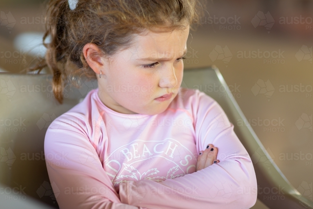 grumpy child with crossed arms - Australian Stock Image