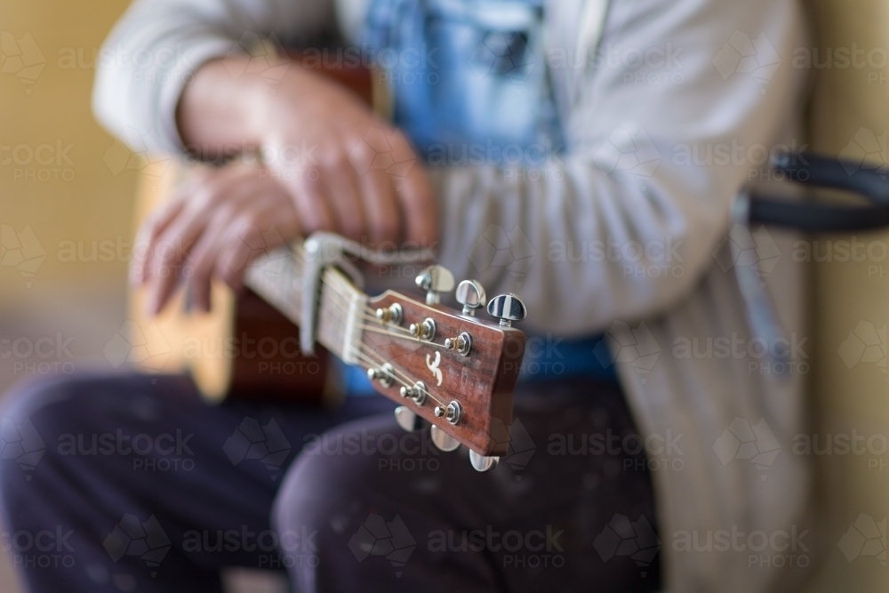 Guitar resting on man's knee - Australian Stock Image