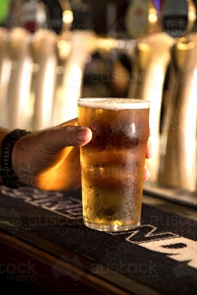 Hand holding a pint of beer - Australian Stock Image