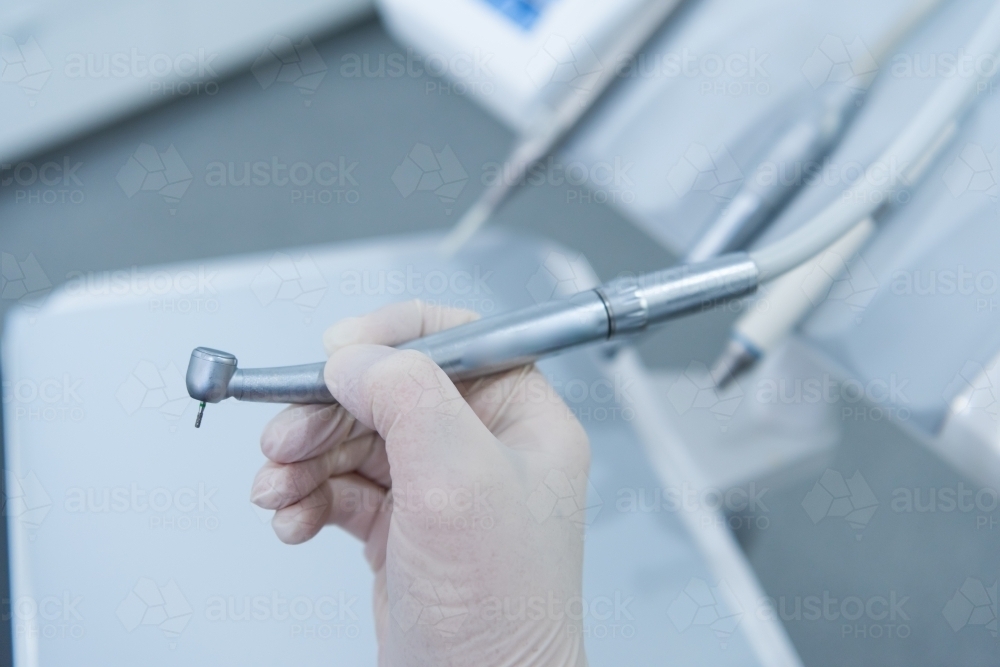 Hand holding dental handpiece - Australian Stock Image