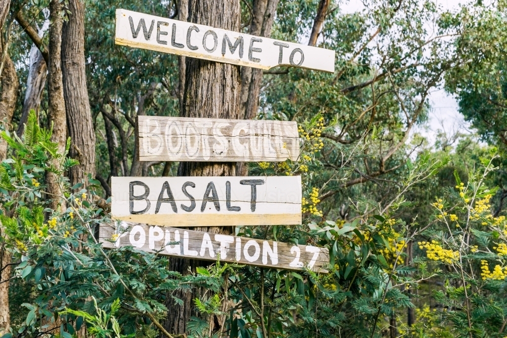 Hand painted sign boards nailed to a gum tree among wattle bushes - Australian Stock Image