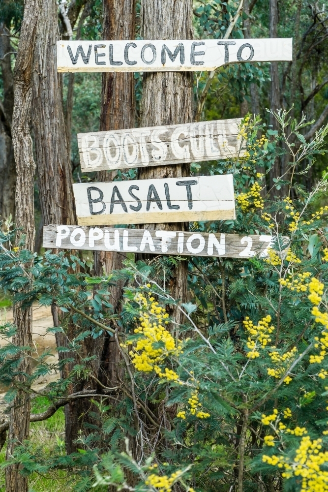 Hand painted sign boards nailed to a gum tree among wattle bushes - Australian Stock Image