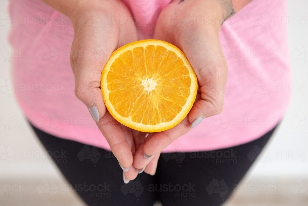 hands holding orange half healthy snack - Australian Stock Image