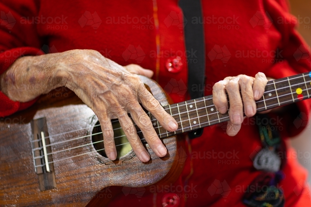 hands of elderly woman holding ukelele - Australian Stock Image